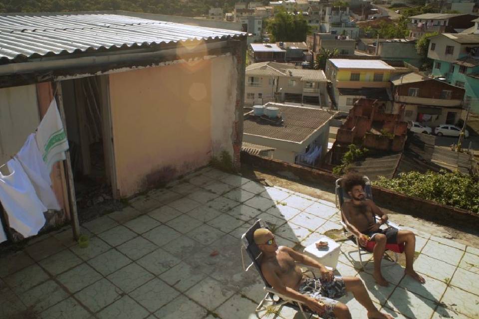 Na imagem dois homens sentados em cadeiras de praia tomando sol