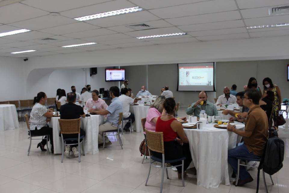 Foto colorida com pessoas sentadas à mesa se alimentando