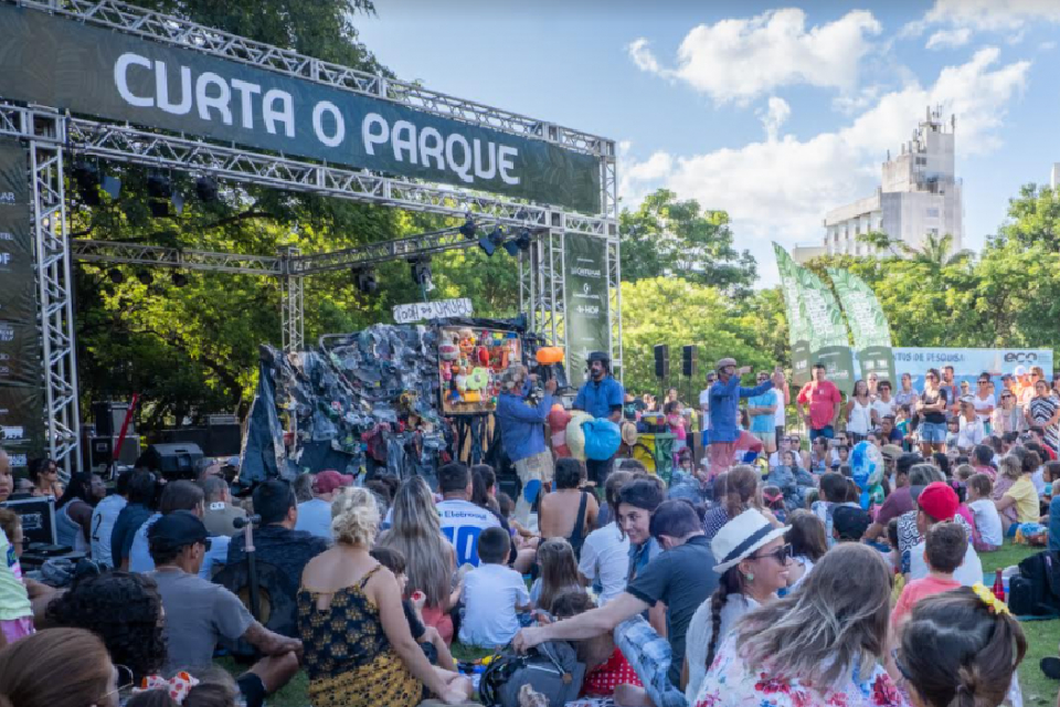 Foto colorida com várias pessoas reunidas em um parque