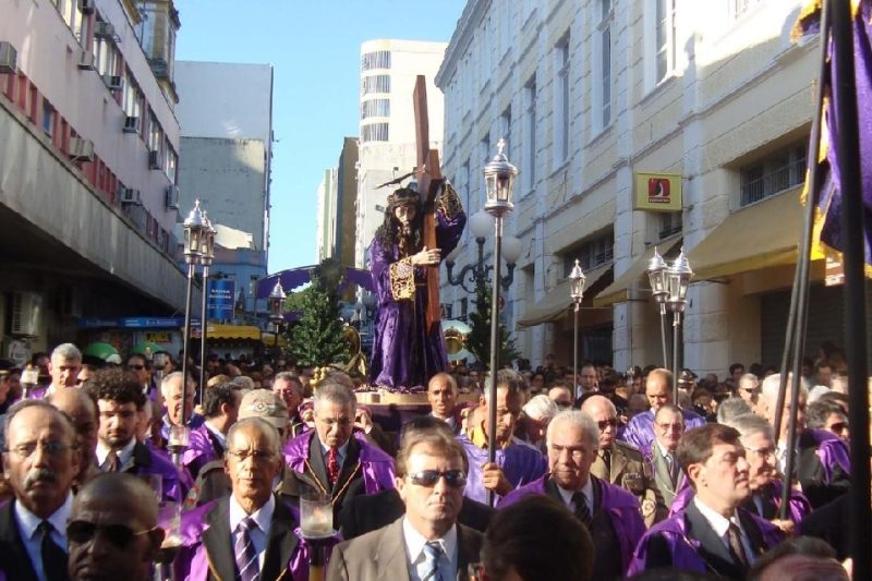 Foto colorida de uma multidão carregando a imagem de Jesus Cristo