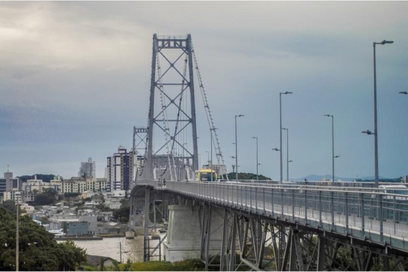 Imagem colorida de uma ponte pênsil com estruturas em ferro na cor cinza