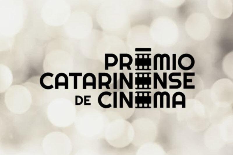 Imagem com fundo desfocado em tons de cinza claro e branco, destacando o texto central "Prêmio Catarinense de Cinema". O texto está disposto em letras maiúsculas pretas, com três ícones de filme entre as palavras, substituindo as letras "O", "A" e "I".