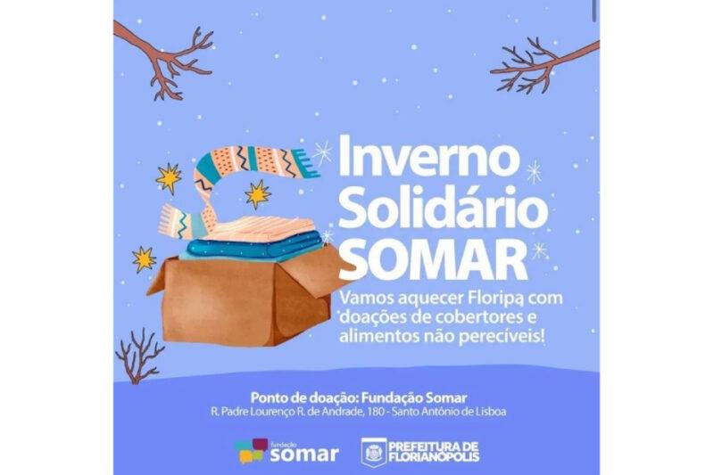 "Cartaz da campanha 'Inverno Solidário SOMAR' com fundo azul claro, flocos de neve e estrelas. No centro, ilustração de caixa de papelão aberta com cobertores e cachecol. Texto: 'Inverno Solidário SOMAR. Vamos aquecer Floripa com doações de cobertores e alimentos não perecíveis!'. Ponto de doação: Fundação Somar, R. Padre Lourenço R. de Andrade, 180 - Santo Antônio de Lisboa. Logotipos da Fundação Somar e da Prefeitura de Florianópolis no rodapé."