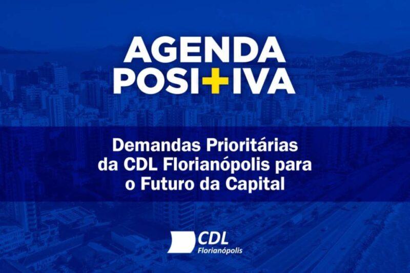 Imagem com fundo azul mostrando uma vista aérea de Florianópolis, destacando prédios altos e uma parte da costa. No topo, em letras grandes e brancas, está escrito "AGENDA POSITIVA", com um símbolo de "+" em amarelo no meio da palavra. Abaixo, em letras brancas, lê-se: "Demandas Prioritárias da CDL Florianópolis para o Futuro da Capital". No rodapé, o logotipo da CDL Florianópolis também em branco. A imagem comunica um foco em planejamento e prioridades estratégicas para a cidade.