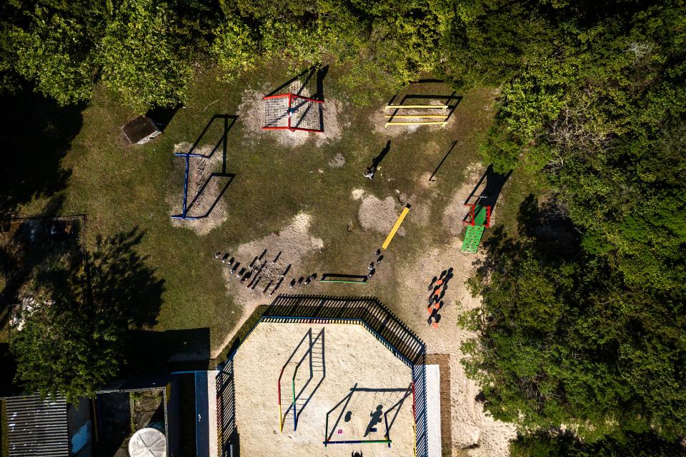 Fotografia aérea de circuito de barras e obstáculos coloridos em área de areia junto à vegetação, com uma pessoa em pé.