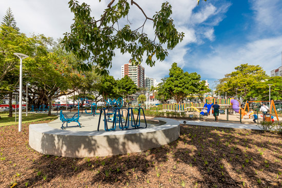 Praça Nossa Senhora de Fátima, com árvores, equipamentos de ginástica ao ar livre e pessoas circulando em área ensolarada.