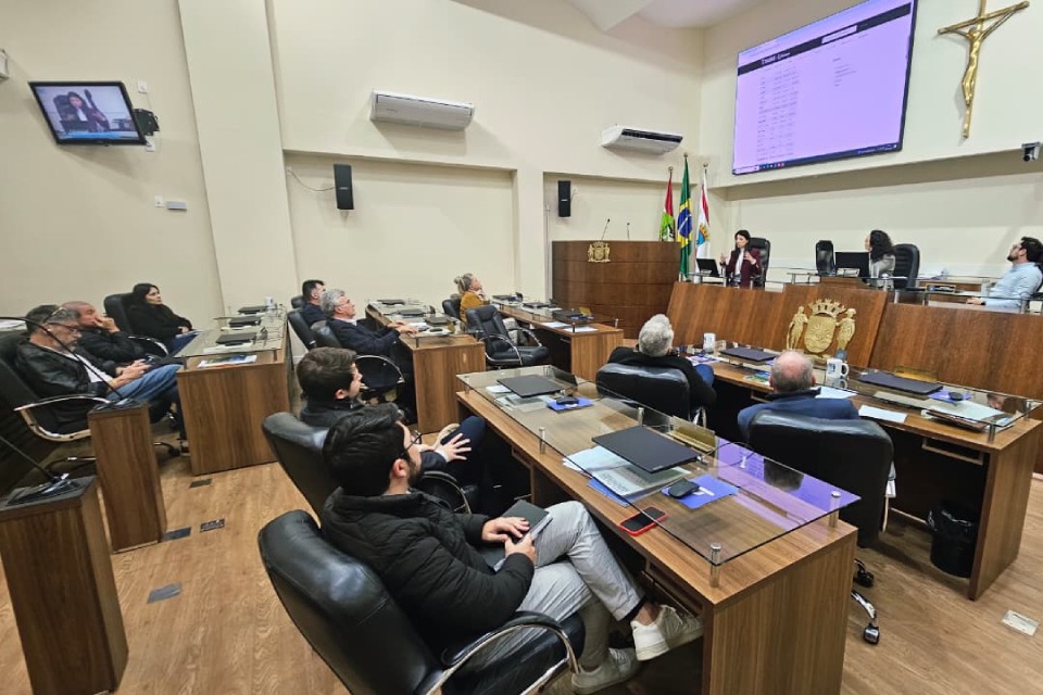 Fotografia de cinco homens em frente ao Plenário Deputado Osni Régis, sobre tapete vermelho.