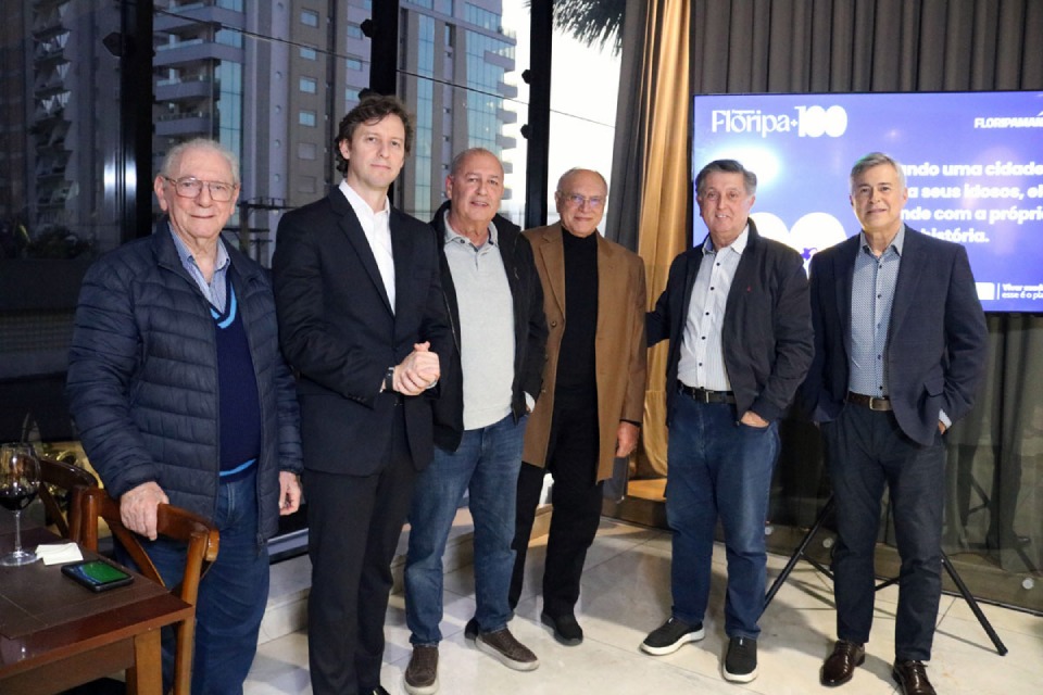 Fotografia de lançamento do Floripa mais cem, com seis homens reunidos ao lado de tela do programa.